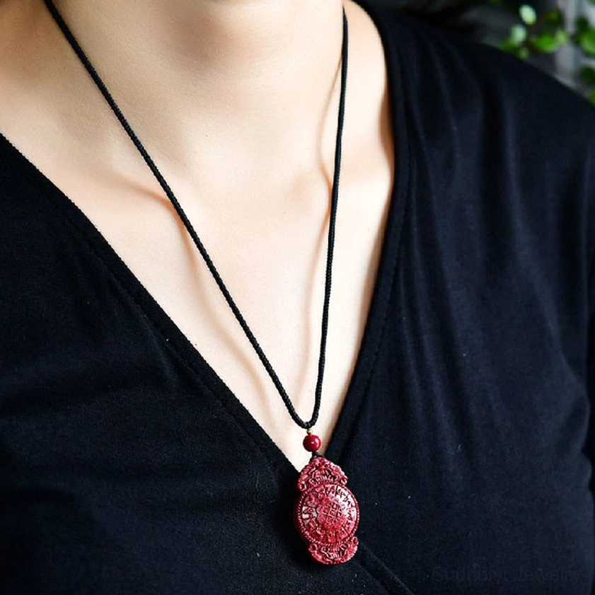 Buddhist cinnabar necklace pendant collection showing laughing Buddha yin yang and zodiac designs on natural display