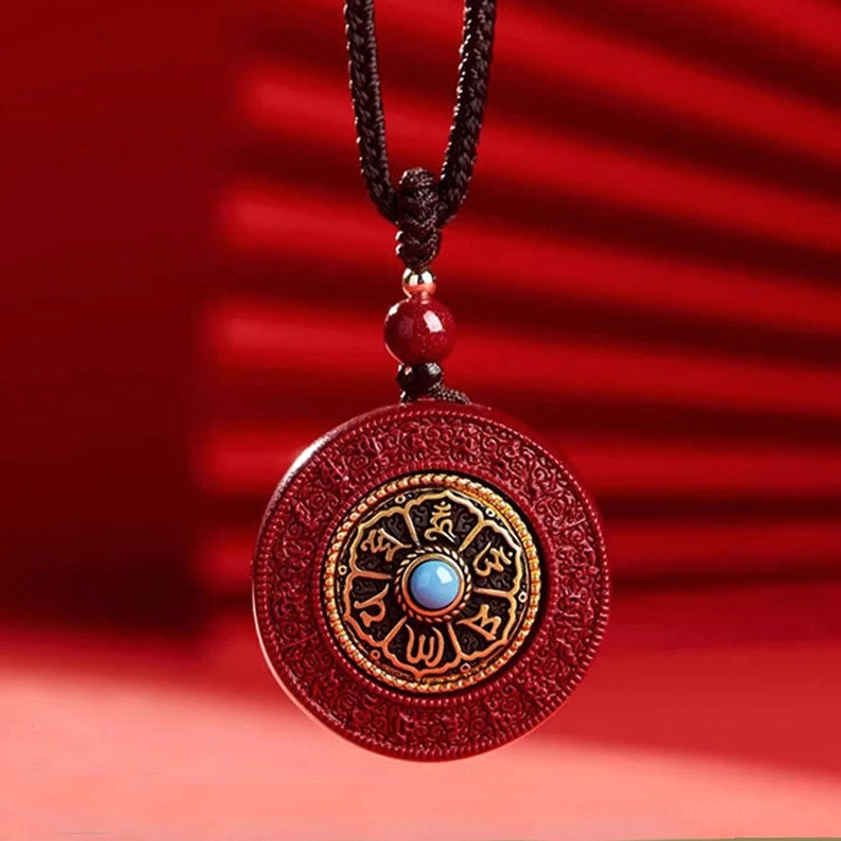 Rotatable cinnabar mantra pendant on brown cord showing intricate gold Sanskrit characters and rotating center medallion