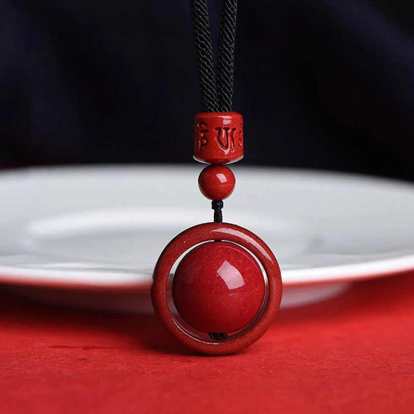 Cinnabar buddhist pendant necklace with black rope showing compact pendant structure and natural stone quality