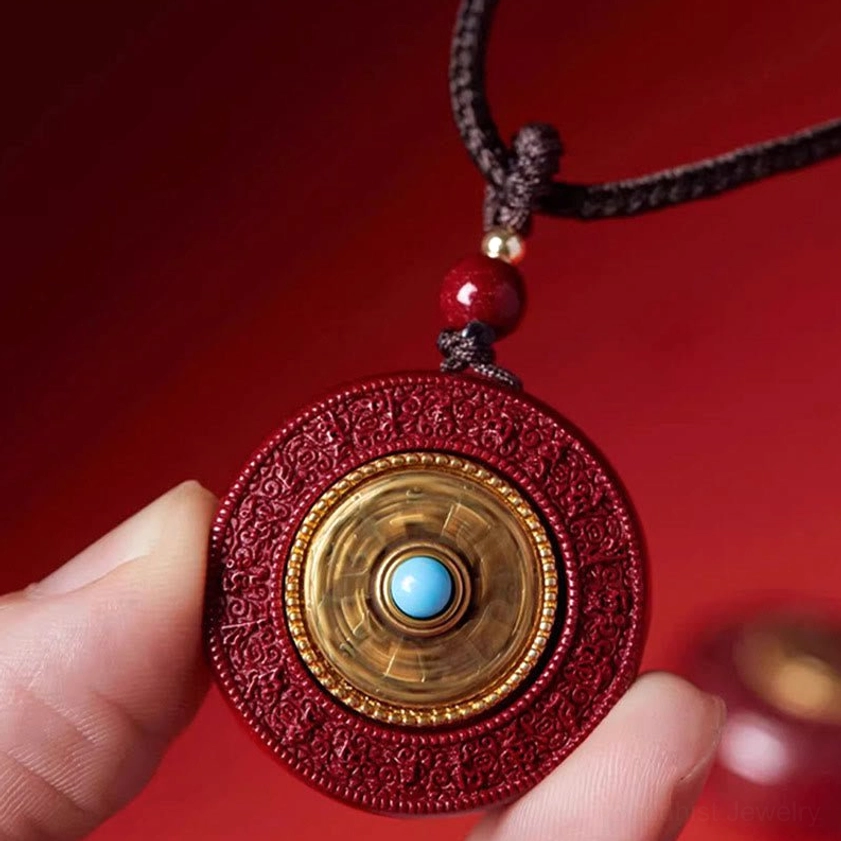 Close-up of rotatable cinnabar pendant showing gold circular border and blue turquoise stone center