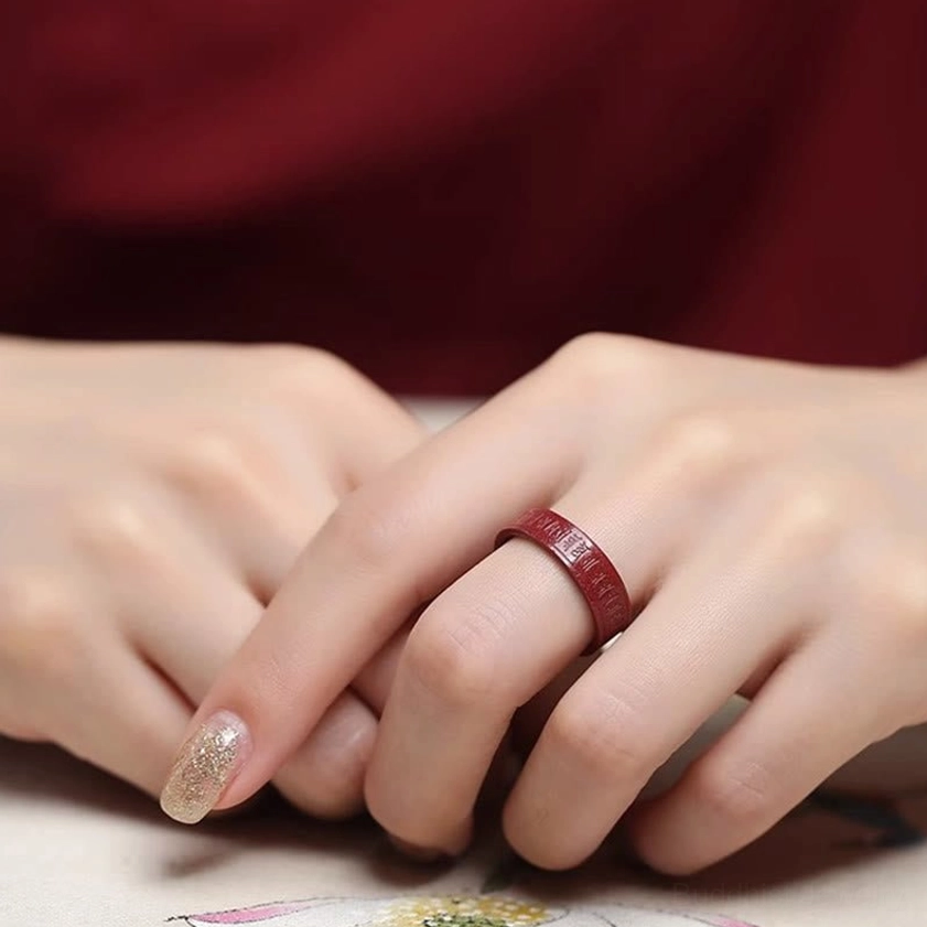 Cinnabar Buddhist engraved ring close-up showing mantra text detail on natural stone surface