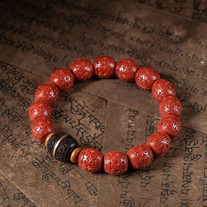 Cinnabar and ebony Buddhist blessing bracelet flat lay with neat circular arrangement of hand-carved beads on traditional Tibetan scripture background