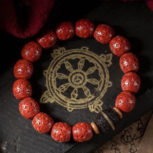 Cinnabar ebony Buddhist blessing bracelet displayed on Tibetan mandala mat with sacred scripture, overhead view showing hand-carved red beads and gold-accented ebony spacers