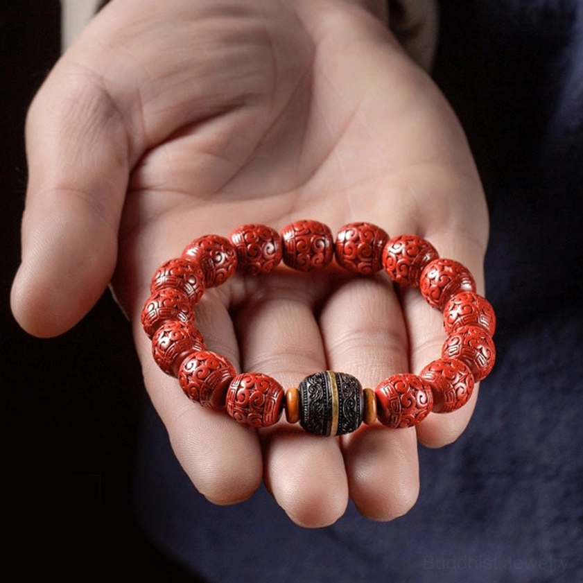 Cinnabar ebony Buddhist blessing bracelet held in open palm against dark blue background, first-person perspective showing complete bracelet circumference
