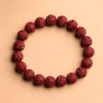 Carved cinnabar Buddhist bracelet with fret pattern design featuring deep wine-red round beads with intricate geometric textures