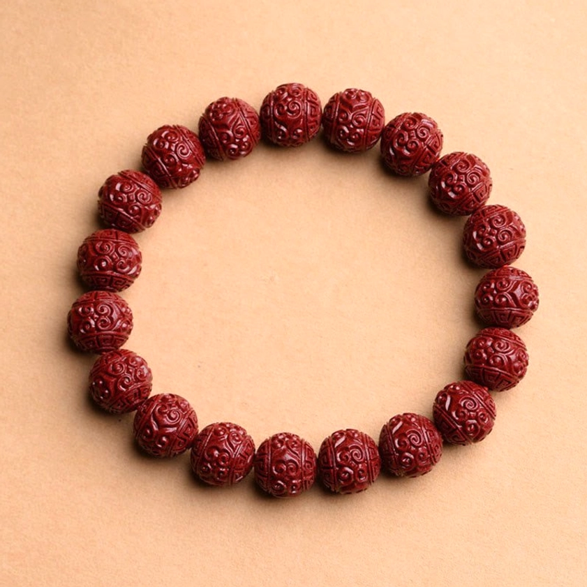 Carved cinnabar Buddhist bracelet with fret pattern design featuring deep wine-red round beads with intricate geometric textures