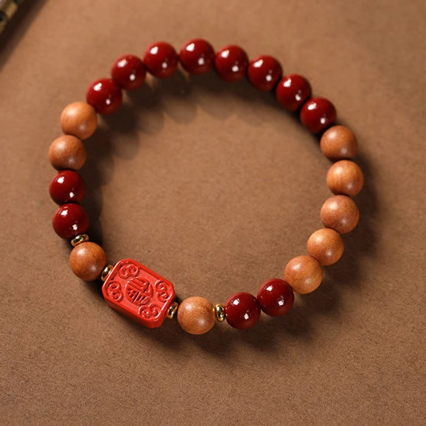 Cinnabar fu character blessing bracelet with red carved fu charm and mixed wood tones elevated flat lay
