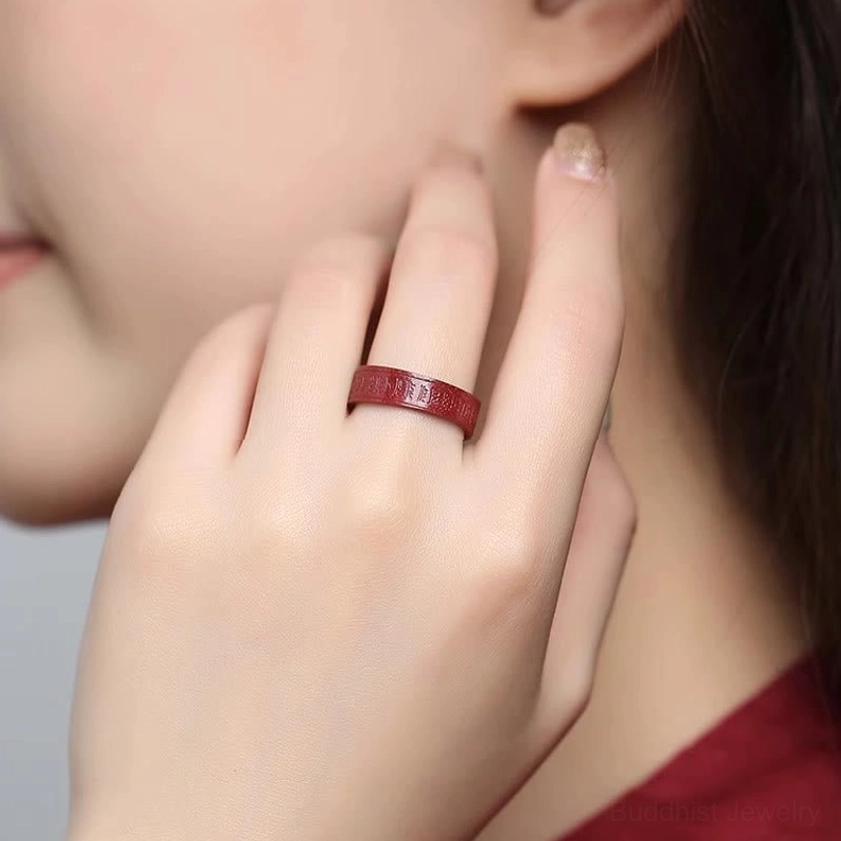 Cinnabar heart sutra ring side profile view showing complete engraved Buddhist sutra on red fabric background