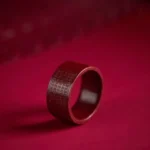 Cinnabar Buddhist mantra ring with engraved Heart Sutra, deep red matte finish, three-quarter side view on dark fabric background