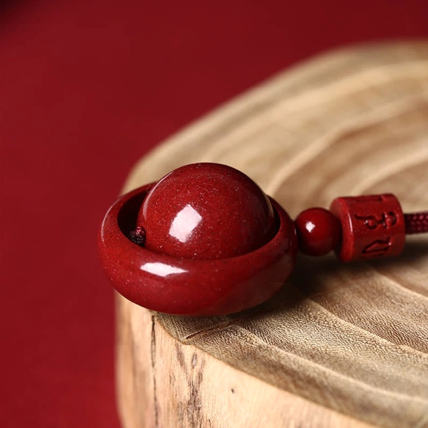 Rotatable cinnabar bead in hollow ring frame with red connecting beads, side close-up detail