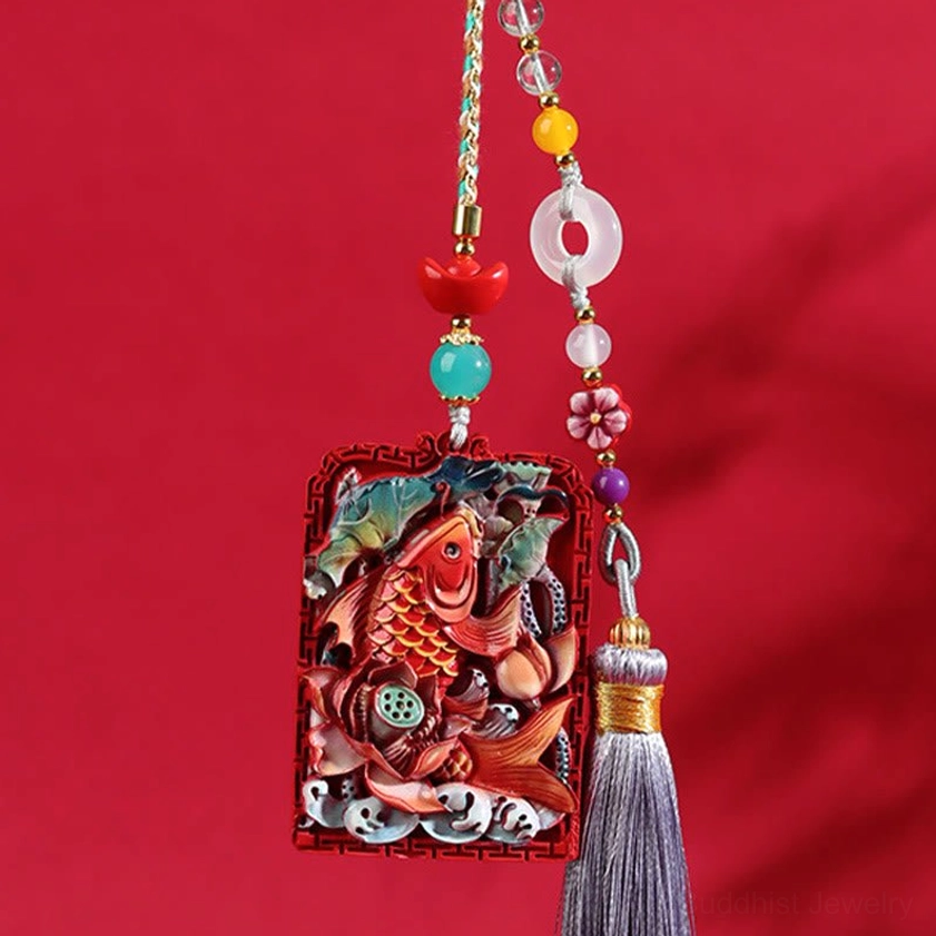 Front view of cinnabar koi lotus car hanging pendant with grey tassel on solid red fabric background