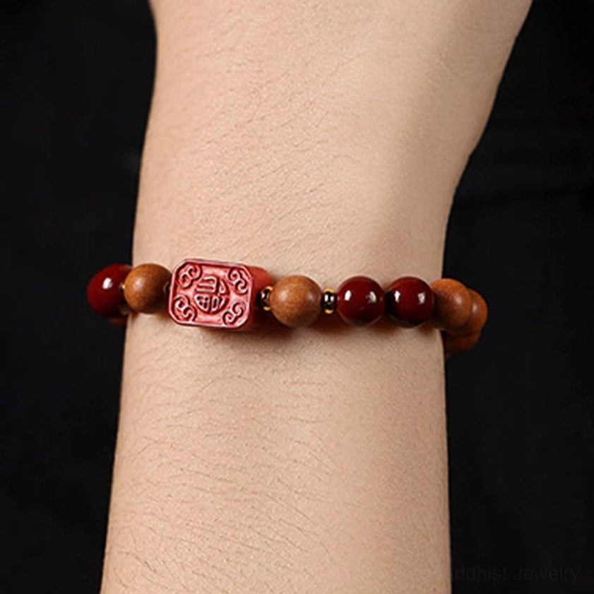 Close-up detail of cinnabar wood beads and lotus charm on handmade Buddhist blessing bracelet