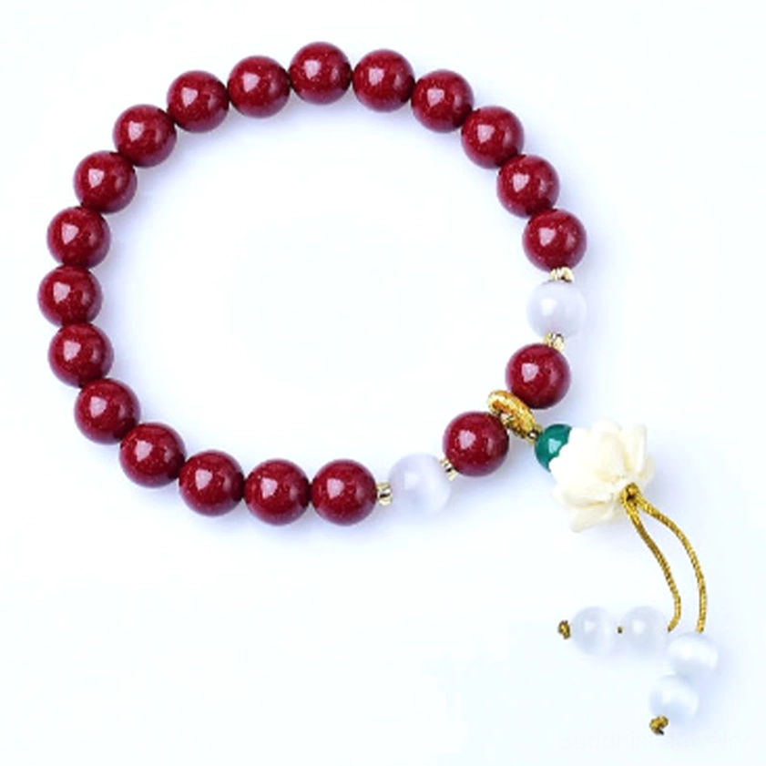 Full overhead view of cinnabar lotus blessing bracelet with mixed spacers, lotus charm, and golden tassel on dark background showing complete bracelet composition