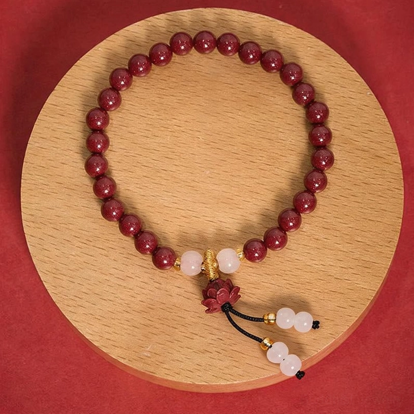 Cinnabar lotus prayer bracelet overhead view with deep red beads and white jade accents on wooden plate, perfect for Buddhist meditation and spiritual practice