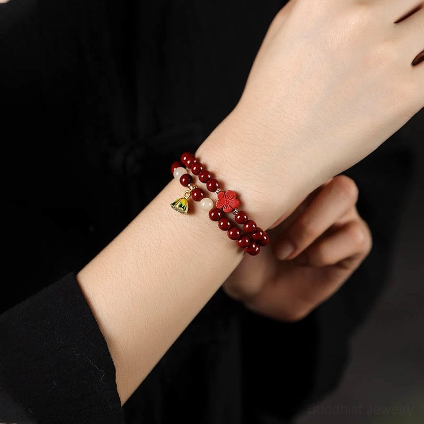 Cinnabar double-wrap blessing bracelet worn on wrist with accent beads and lotus flower pendant