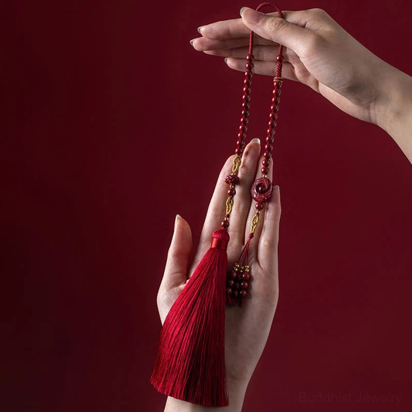 Natural cinnabar lotus car hanging decoration with red silk tassel and golden hardware displayed in hands