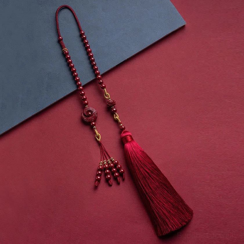Top-down flat lay view of cinnabar lotus hanging decoration showing dual red tassels and beaded charms