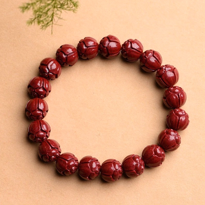 Lotus carved cinnabar Buddhist bracelet with delicate lotus flower pattern on wine-red stone beads, symbol of enlightenment