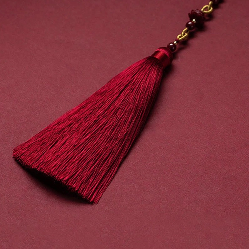 Cinnabar lotus car hanging decoration with long red silk tassel and beaded chain on dark background