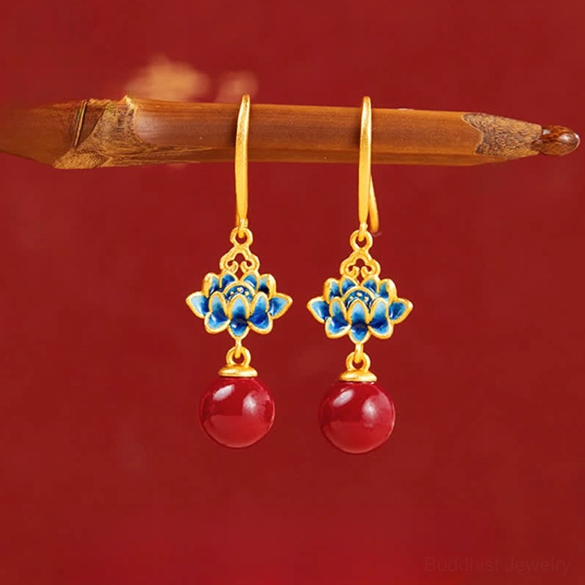 Cinnabar lotus drop earrings with gold sterling silver hooks and blue enamel lotus charms on red background - top view