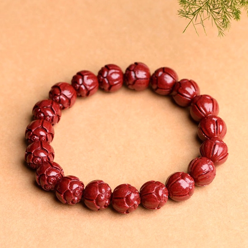 Handcrafted cinnabar lotus bracelet with clear lotus flower carvings on wine-red stone, complete elastic bracelet