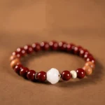 Handmade cinnabar wood lotus fu character blessing bracelet overhead flat lay view with white lotus bead and mixed reddish-brown sandalwood beads on warm background