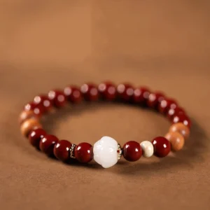 Handmade cinnabar wood lotus fu character blessing bracelet overhead flat lay view with white lotus bead and mixed reddish-brown sandalwood beads on warm background