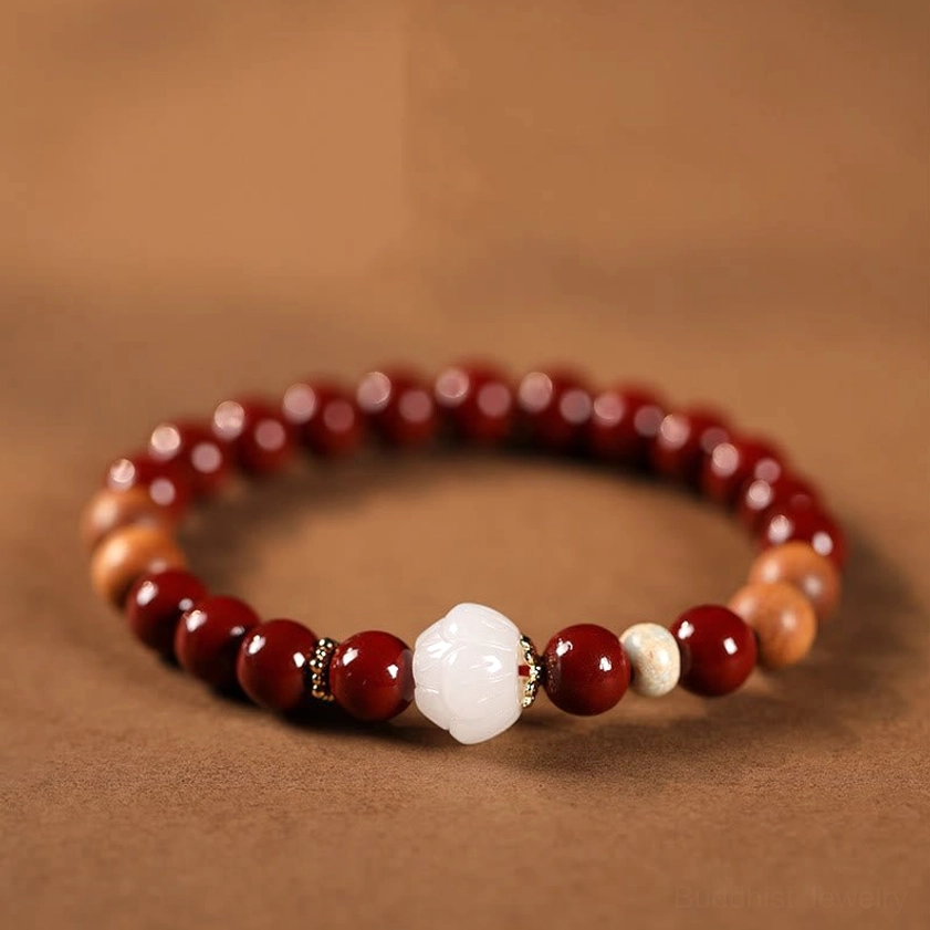 Handmade cinnabar wood lotus fu character blessing bracelet overhead flat lay view with white lotus bead and mixed reddish-brown sandalwood beads on warm background