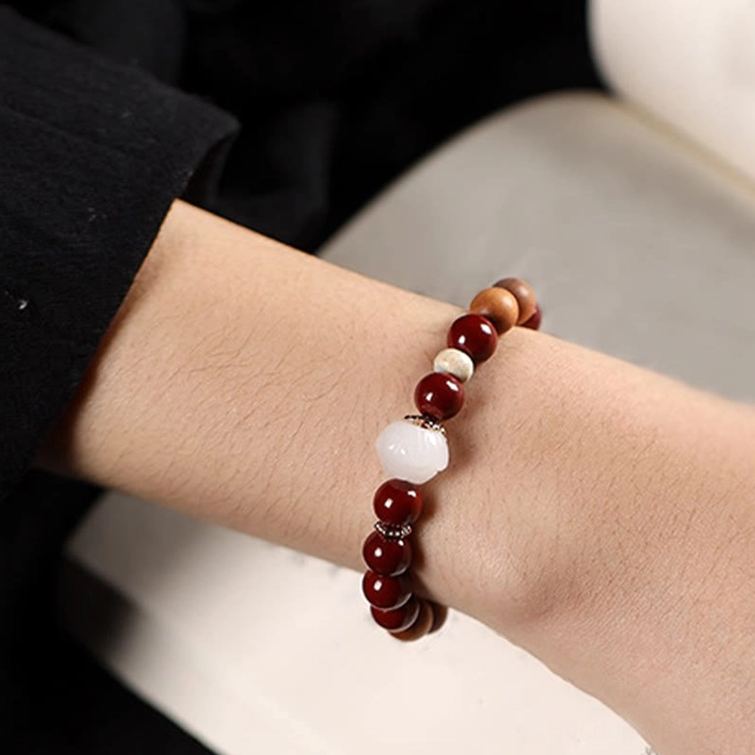 Buddhist blessing bracelet worn on arm demonstrating fit and elastic design with cinnabar beads and lotus charm