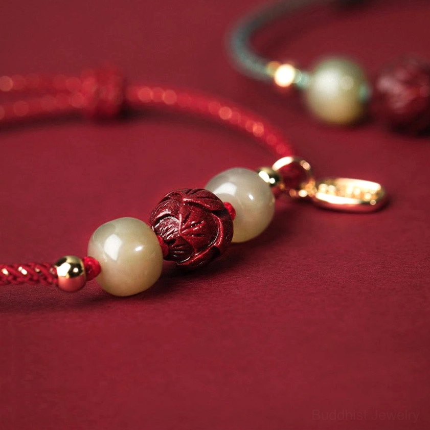 Close-up detail of hand-carved cinnabar lotus pendant and polished Hetian jade beads with 14K gold spacers, side angle view showing craftsmanship