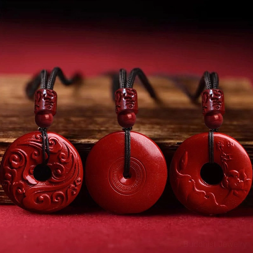 Three variations of cinnabar lotus peace buckle Buddhist necklaces showcasing smooth and carved designs, displayed with decorative accessories on wooden base