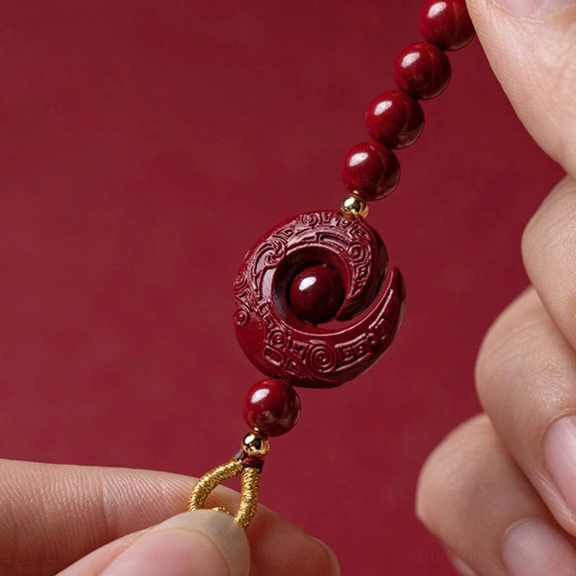 Close-up detail of carved natural cinnabar lotus pendant with glossy beads and rotatable inner bead