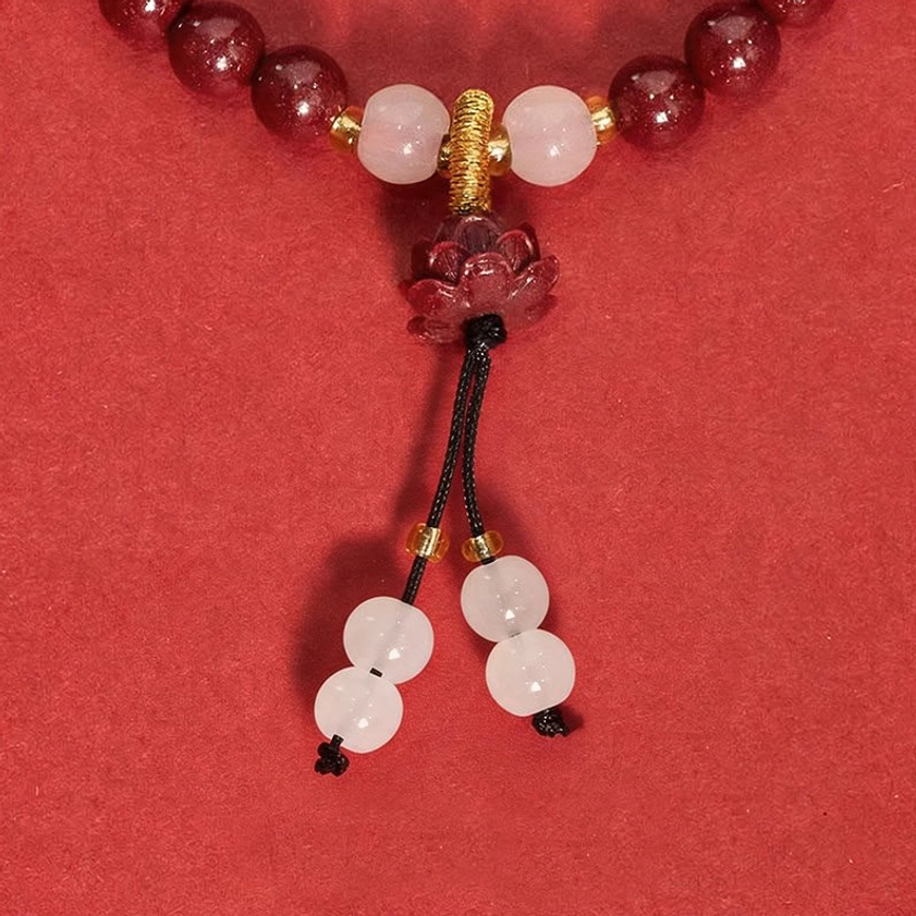 Macro detail shot of cinnabar lotus pendant and tassel showing handmade artisan quality and Buddhist symbol craftsmanship