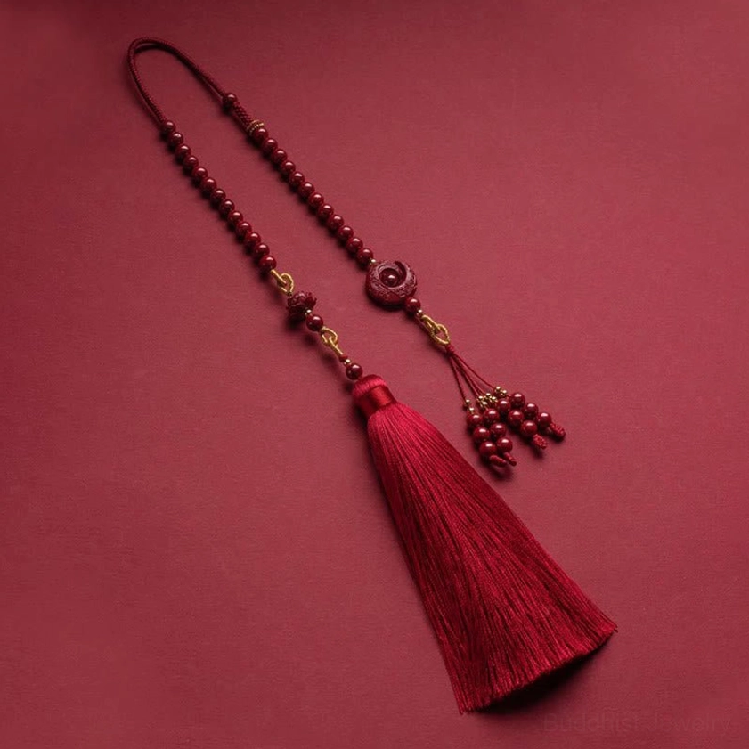 Close-up of red silk tassel component with golden metal cap and connected beaded chain