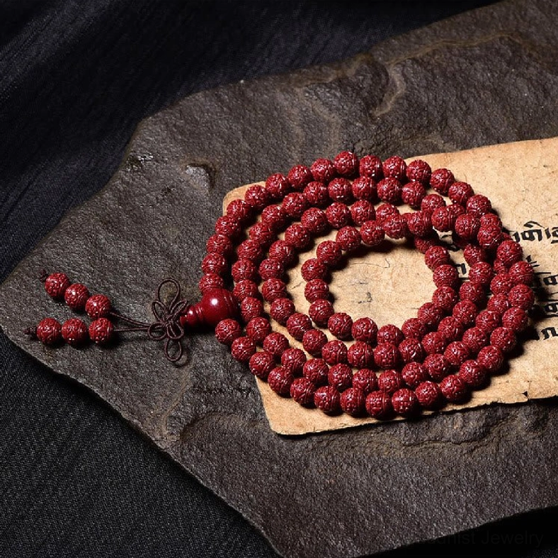 Carved cinnabar 108 mala beads on stone slab with traditional tassel decor and vintage script paper