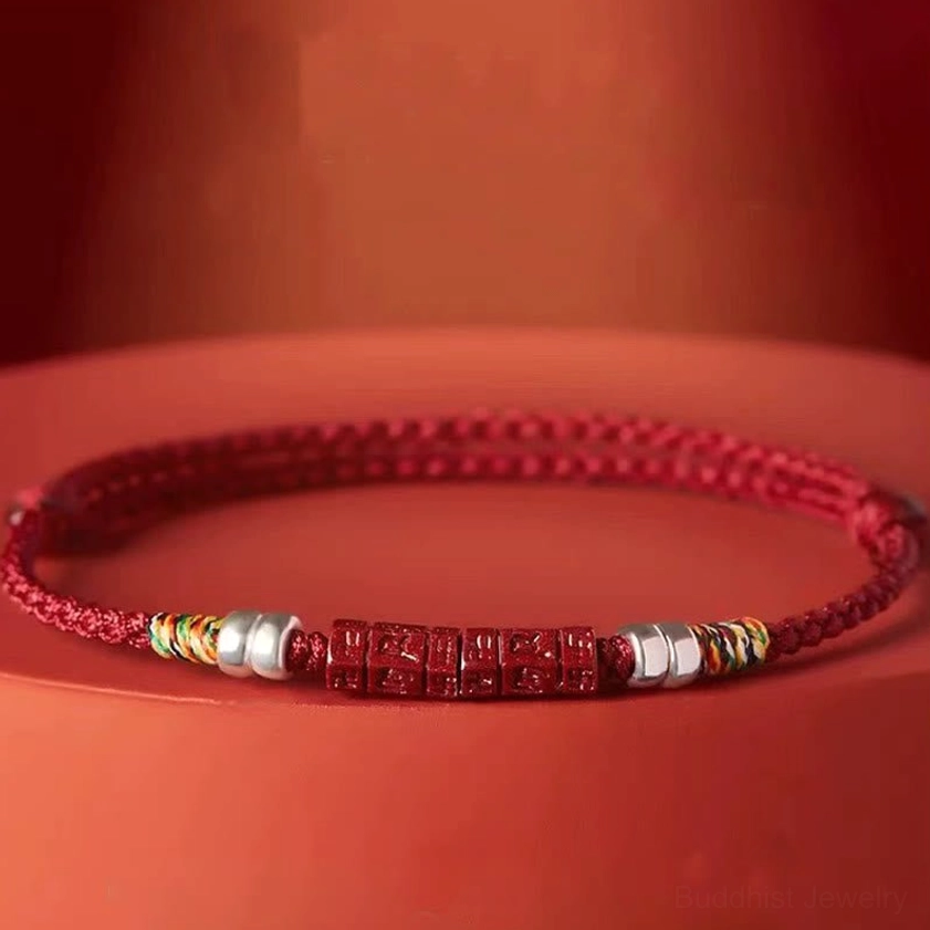 Close-up side view of cinnabar blessed bracelet with engraved Om Mani Padme Hum beads and silver accents on display stand