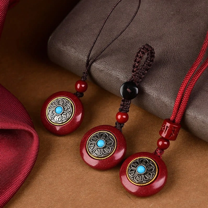 Buddhist mantra pendant flat lay on leather notebook showing braided red silk cord and blessing accessory styling