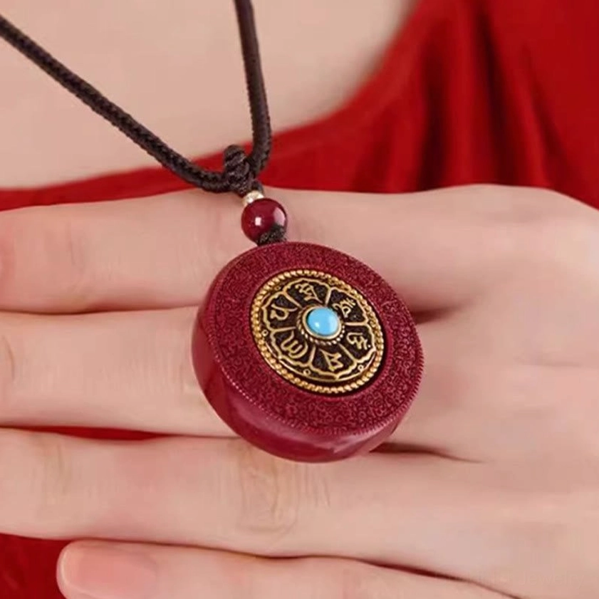 Hand-held cinnabar Buddhist pendant necklace in palm showing smooth red stone and turquoise inlay detail