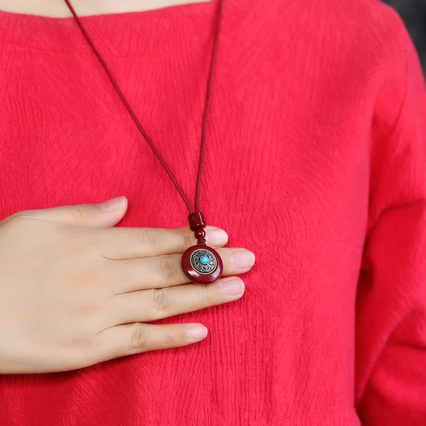 Model wearing cinnabar Om Mani Padme Hum pendant necklace with red braided cord on body