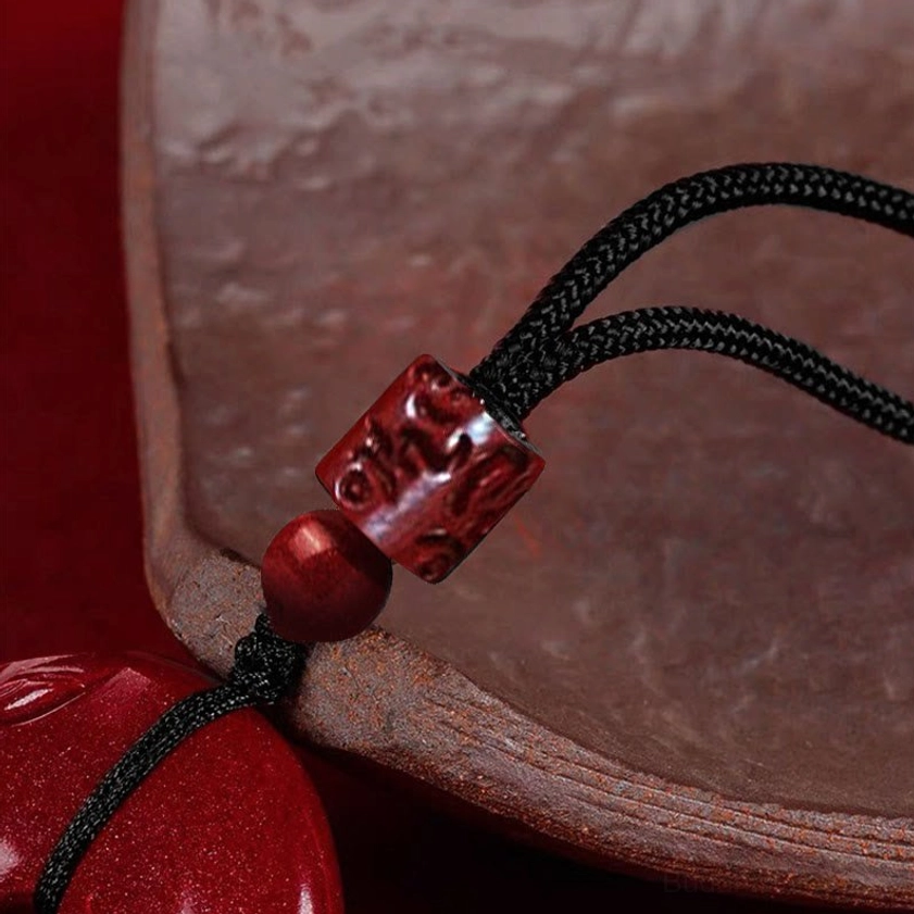 Cinnabar necklace component details showing carved cylindrical spacer bead and round cinnabar bead with black braided rope for Buddhist jewelry assembly