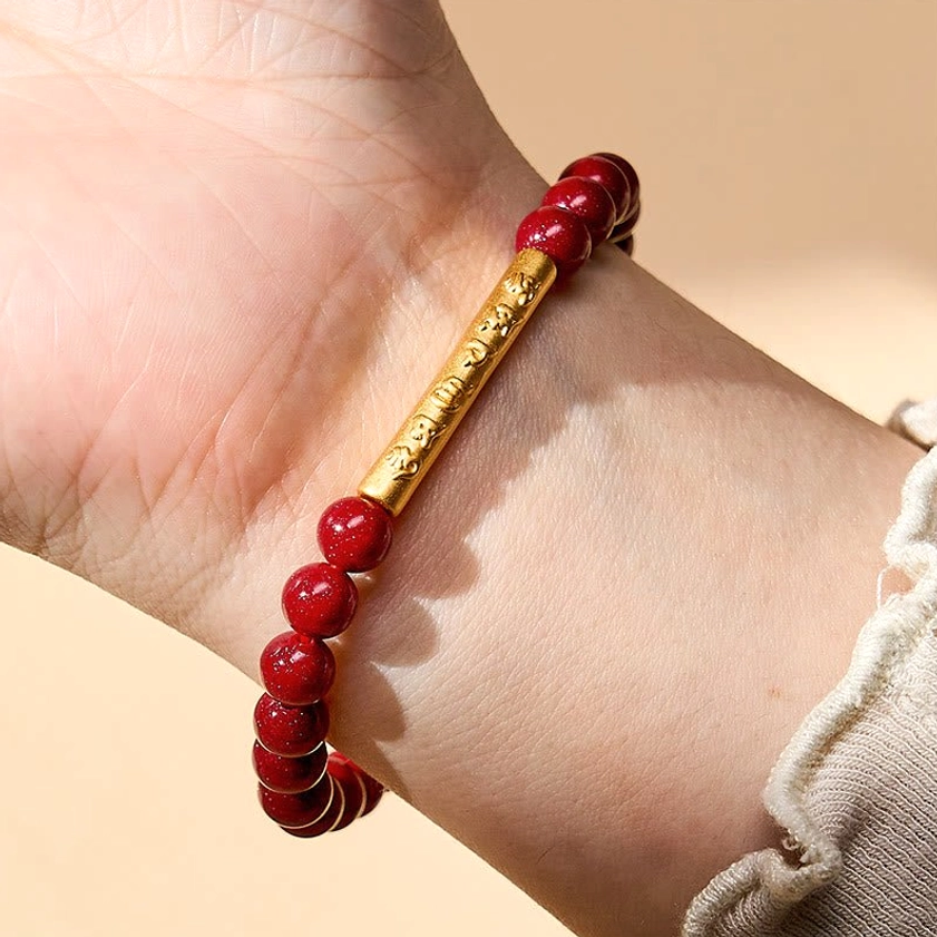 Cinnabar mantra bracelet worn on wrist with frilled sleeve, demonstrating proper fit and comfortable sizing for daily spiritual practice