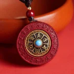 Red cinnabar Buddhist pendant necklace with Om Mani Padme Hum mantra and gold engraved disc, overhead view on terracotta background