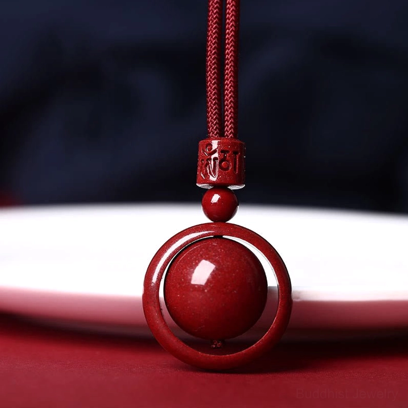 Cinnabar om mani padme hum pendant necklace with red rope, overhead close-up view showing carved mantra details