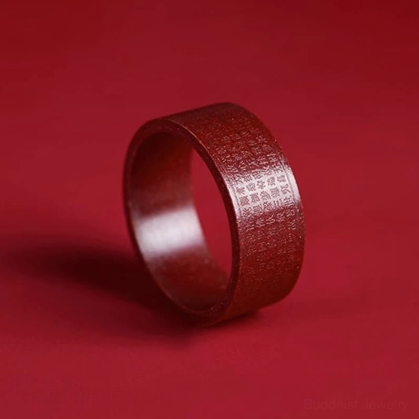Cinnabar om mani padme hum ring profile view showing engraved mantra around band on red background