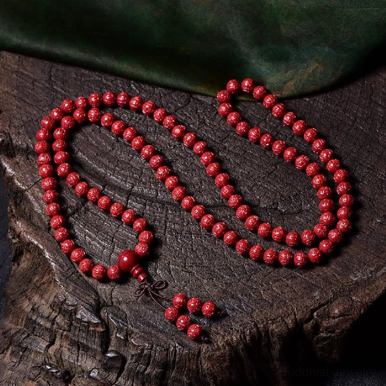Plain smooth round cinnabar 108-bead mala with tassel on dark wood green fabric background
