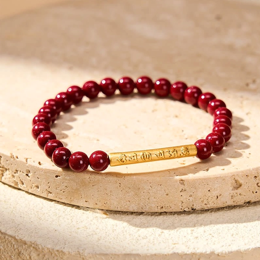 Handcrafted cinnabar mantra bracelet with sterling silver accent on textured stone, showing matte red beads and polished metal details