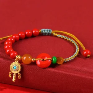 Cinnabar Peace Buckle Buddhist string bracelet flat lay with multi-color braided cord and gold charm on red background
