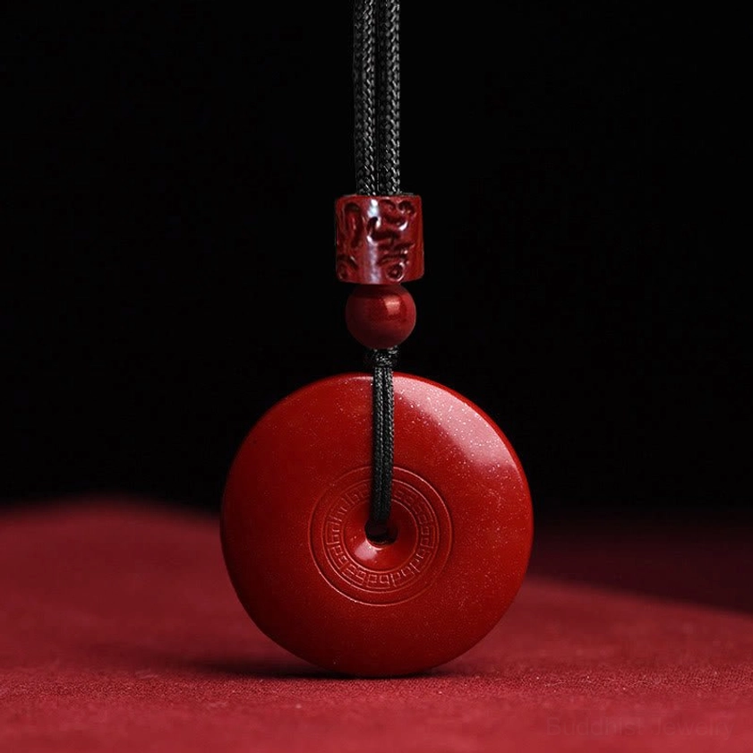 Back view of smooth cinnabar peace buckle necklace showing circular engraved pattern and polished natural cinnabar surface for Buddhist meditation practice