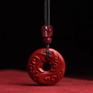 Handcrafted cinnabar peace buckle necklace with embossed cloud pattern, featuring deep red natural cinnabar pendant on black braided cord for Buddhist meditation and spiritual protection