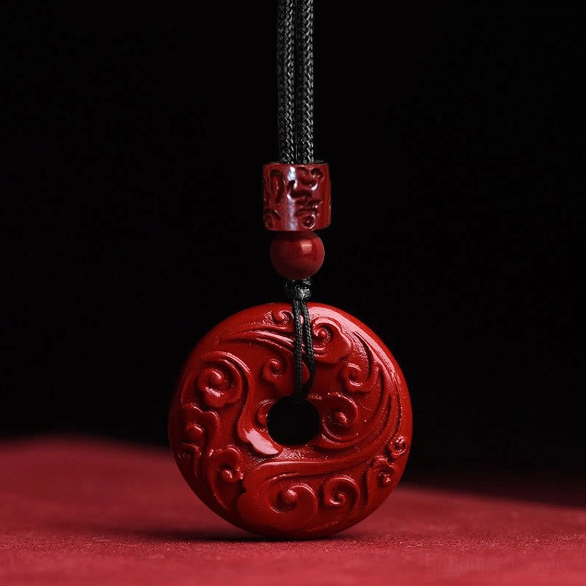 Handcrafted cinnabar peace buckle necklace with embossed cloud pattern, featuring deep red natural cinnabar pendant on black braided cord for Buddhist meditation and spiritual protection